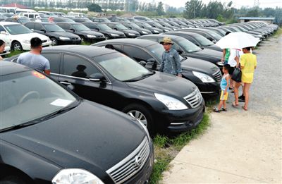 昨日，市民在山東棗莊一家拍賣公司場地上查看待拍賣公車。當(dāng)日，棗莊市103輛公車公開拍賣。新華社記者