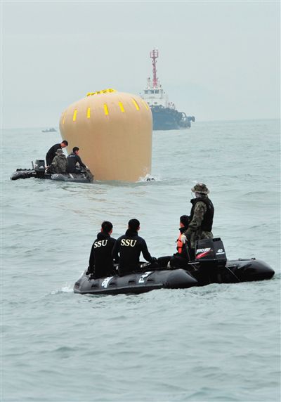 18日，搜救人員準備將氣囊捆綁到沉沒客輪上。
