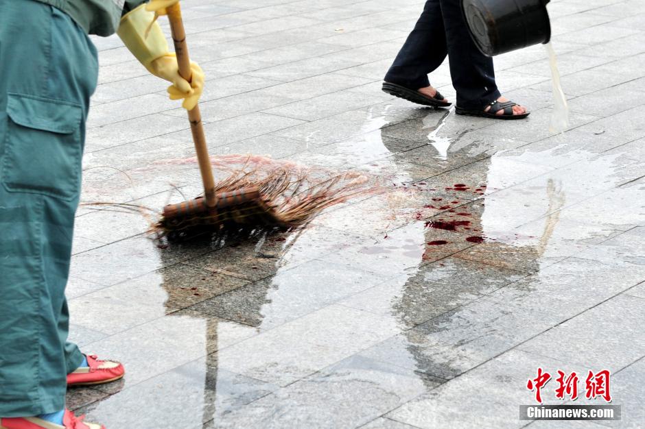 圖為環(huán)衛(wèi)工人在清理案發(fā)地點(diǎn)的血跡。