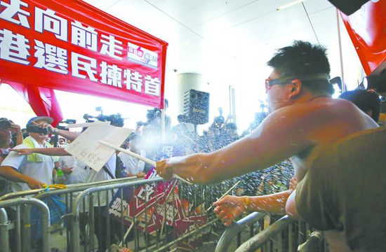 17日，在香港立法會外，一名反對政改的男子向支持派人群投擲標(biāo)牌。