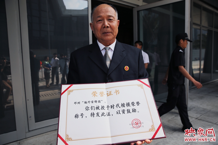 河南鄧州“編外雷鋒團”團長宋清梅向眾多記者展示中宣部授予的“時代楷模”榮譽證書。