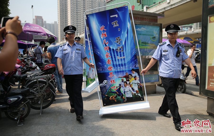 7月2日上午，鄭州市紫荊山地鐵站出入口，執(zhí)法人員抬著寫有勸導(dǎo)語的宣傳板，前往占道經(jīng)營(yíng)攤位“圍觀執(zhí)法”