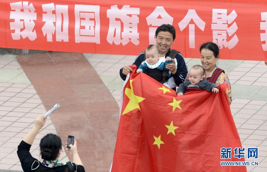 9月27日，在山東德州市中心廣場(chǎng)，市民與國旗合影。