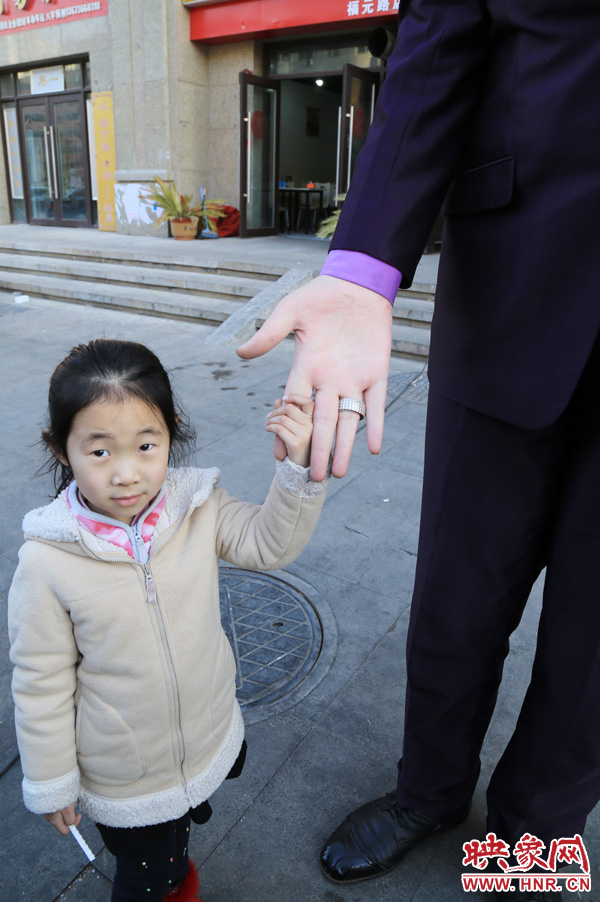 巨人“張歡”牽著一名漂亮的小女孩，兩人的手大小對比非常明顯。